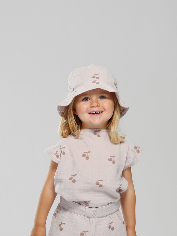 Summer bucket hat in soft muslin fabric. Lilac with darker cherry print. XS and S has strings that can be tied underneath chin. 